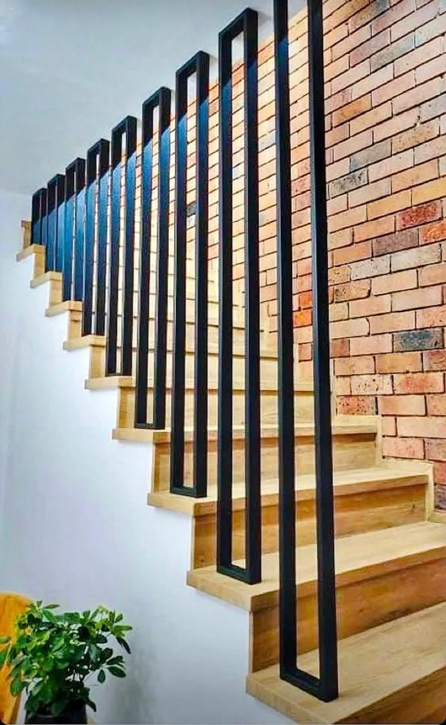 Holztreppe mit modernem Design-Geländer vor Backsteinwand